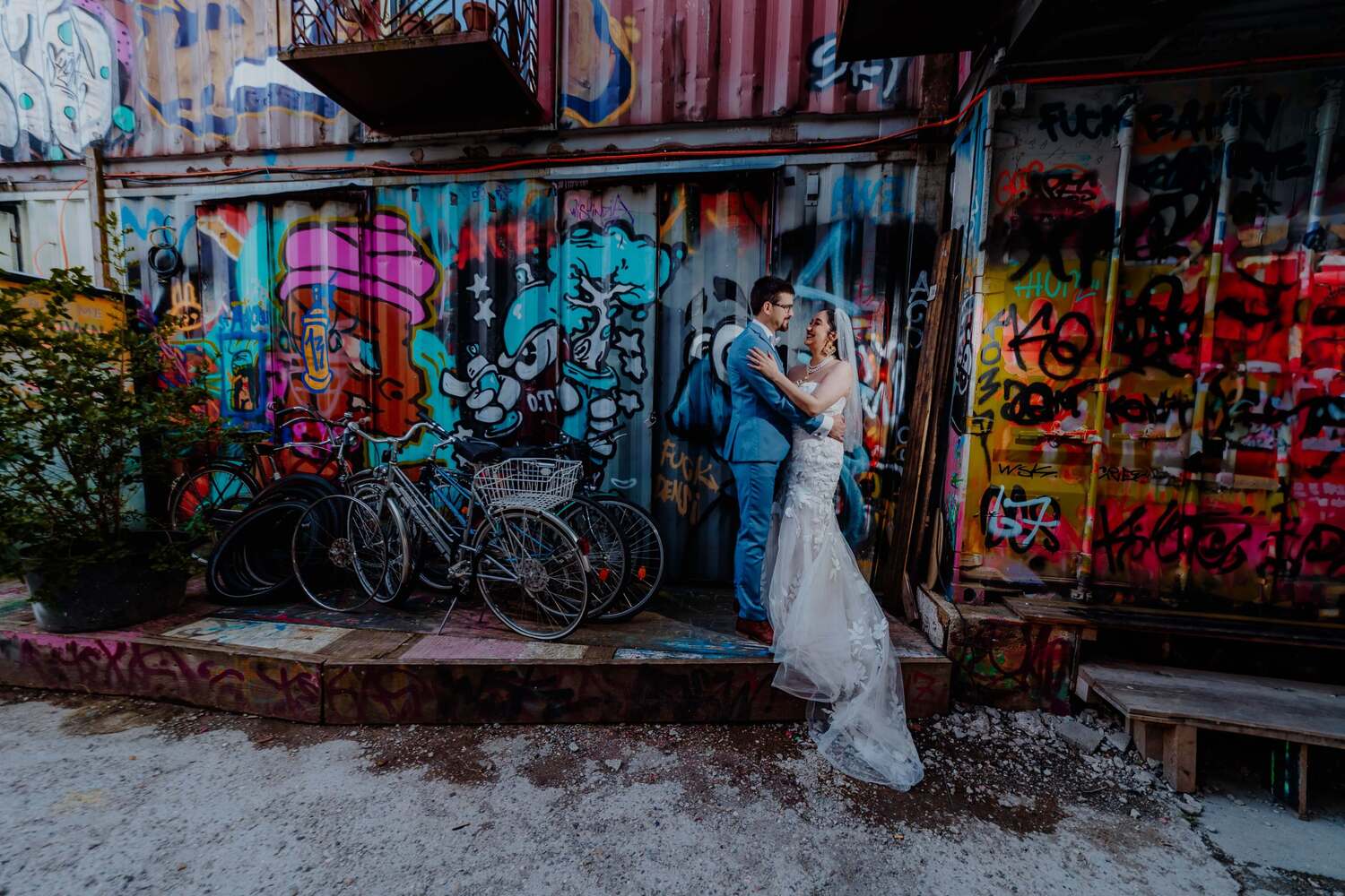 Ein Paar, das sich nach der Hochzeit vor einem Graffiti in München umarmt.
