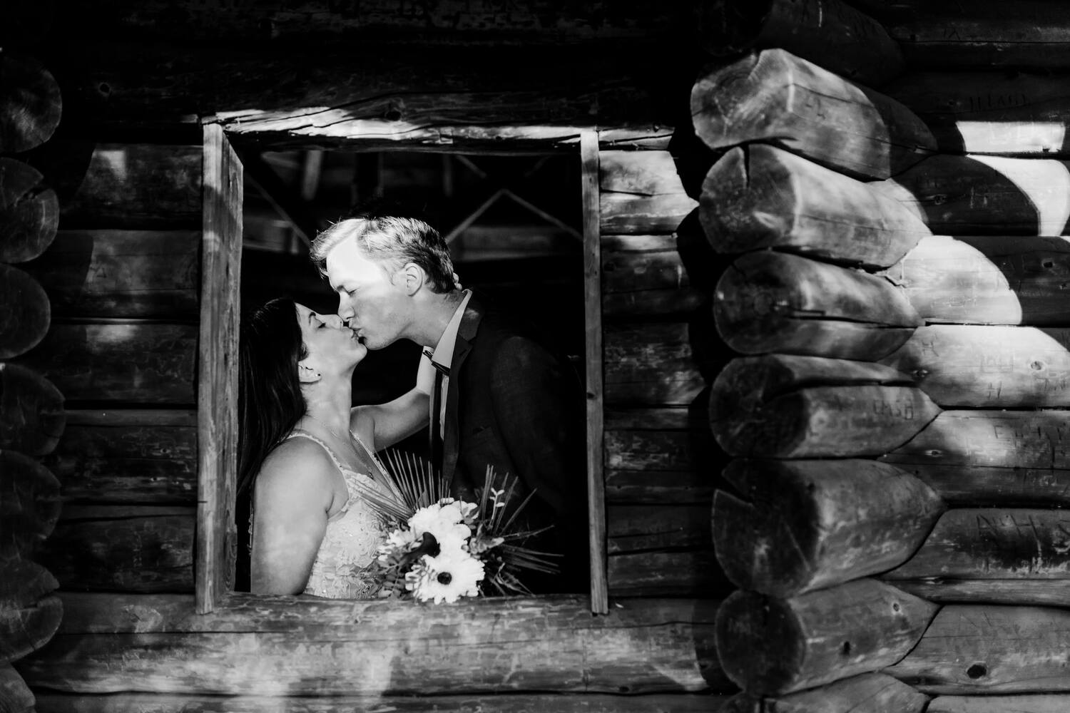 Ein Hochzeitspaar küsst sich leidenschaftlich in einer Holzhütte
